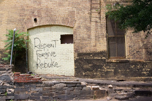 Rebuke Graffitti on a white brick building.