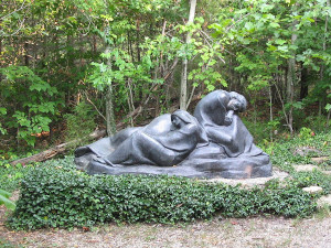 A statue of sleeping disciples outside in a park.