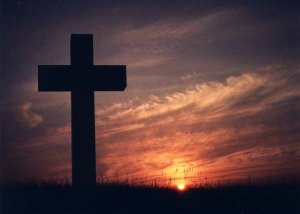 Picture of a cross on a hill with a red sky sunset in the background.