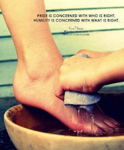 Two hands washing a foot over a wooden bowl.